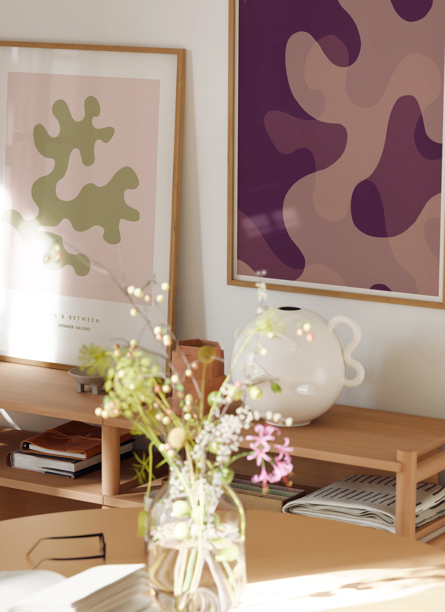 Lifestyle image with art print of large warm violet oak leaf shapes in natural wooden frame.