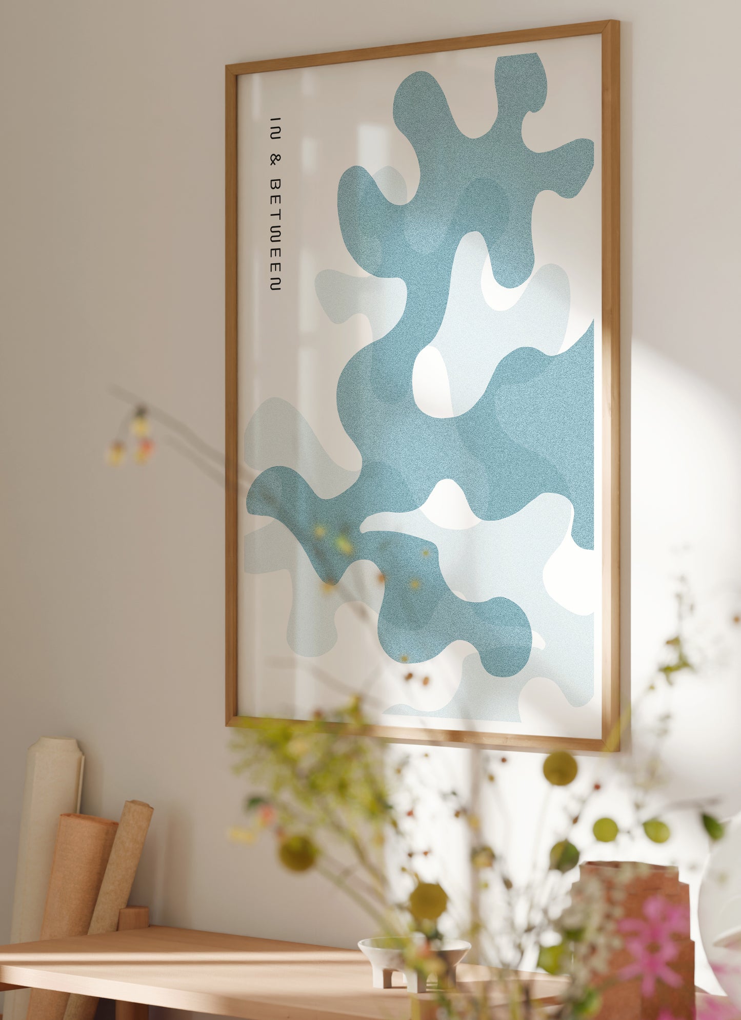 Lifestyle image with art print of pastel blue oak leaves on white background in natural wooden frame.